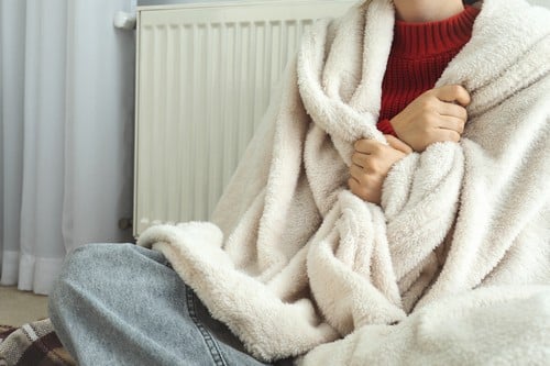 chauffagiste Ermont - Une femme se réchauffe devant son radiateur