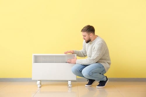 chauffagiste Gagny - Un homme se réchauffe près d'un radiateur