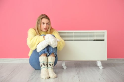 chauffagiste-Gonesse - Une femme se réchauffe près de son radiateur