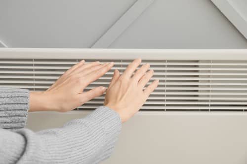 chauffagiste Grande-Synthe - Une femme se réchauffe les mains devant son radiateur