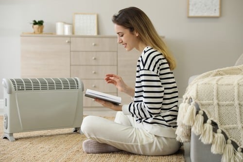 chauffagiste Hérouville-Saint-Clair - Une femme se réchauffe près de son radiateur