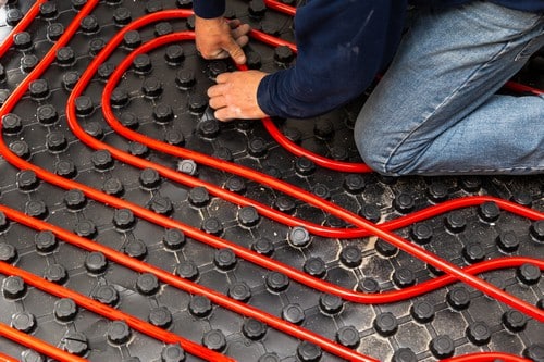 chauffagiste Houilles - Un homme installe un plancher chauffant.