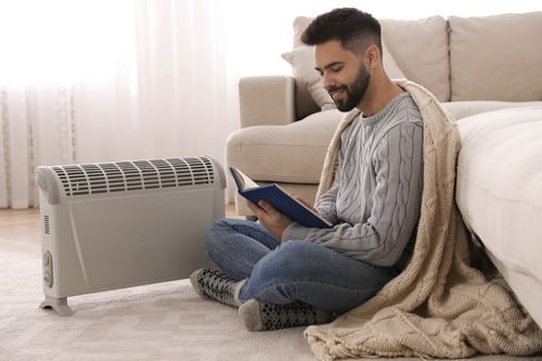 chauffagiste Illkirch-Graffenstaden - Un homme se réchauffe près d'un radiateur