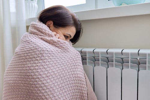 chauffagiste Istres - Une femme se réchauffe près d'un radiateur