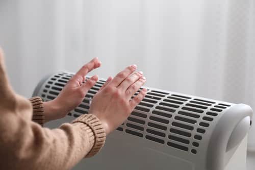 chauffagiste La Garenne-Colombes - Une femme se réchauffe les mains près d'un radiateur
