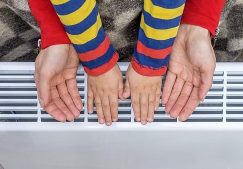 chauffagiste Le Cannet - Un enfant et sa mère se réchauffe les mains sur un radiateur.