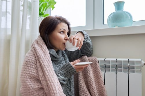 chauffagiste Le Plessis-Robinson - Une femme se réchauffe près de son radiateur