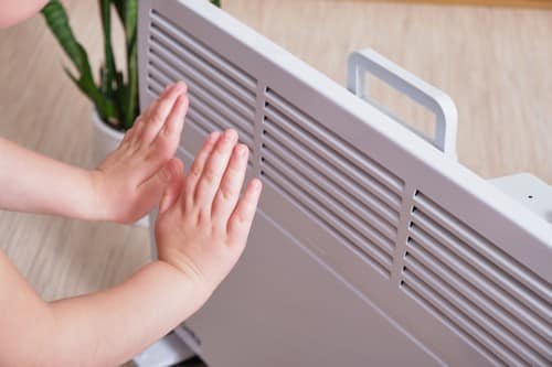 chauffagiste Longjumeau - Se réchauffer les mains près d'un radiateur