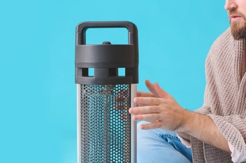 chauffagiste Mandelieu-la-Napoule - Un homme se réchauffe les mains devant son radiateur électrique