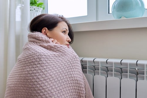 chauffagiste Montmorency - Une femme se réchauffe près de son radiateur
