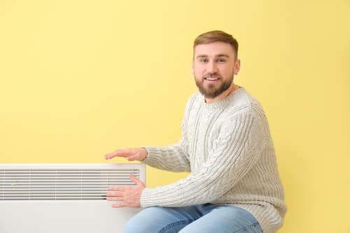 chauffagiste Périgueux - Un homme se réchauffe à côté de son radiateur