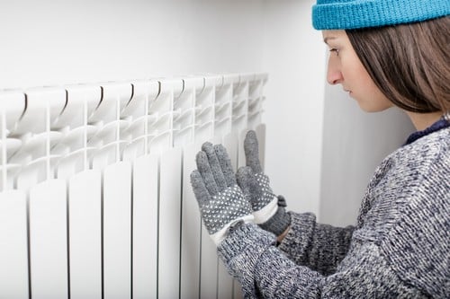 chauffagiste Pontault-Combault - Une femme se réchauffe les mains sur un radiateur.