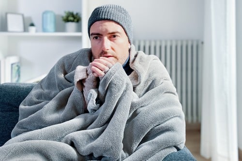 chauffagiste Rambouillet - Un homme se réchauffe devant son radiateur