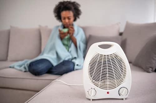 chauffagiste Ris-Orangis - Une femme se fait réchauffer par un radiateur électrique