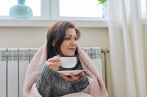chauffagiste Yerres - Une femme boit son café avec son radiateur chaud