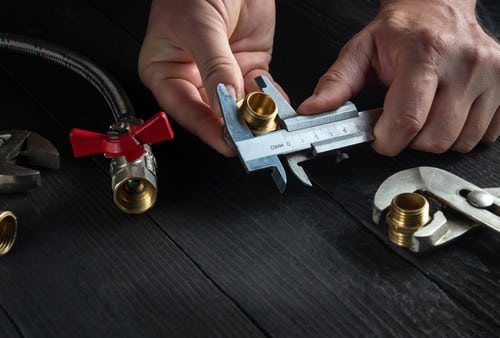 plombier Bruay-la-Buissière - un artisan mesure des raccords en laiton.