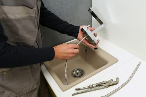 plombier Fécamp - Un technicien installe un mitigeur dans une cuisine.