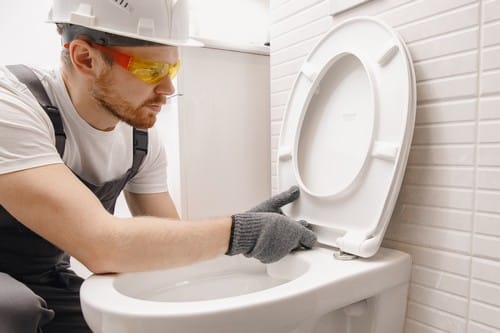 plombier Olivet - Un technicien installe un cuvette de toilettes.