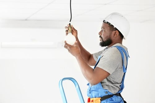 électricien Bourg-la-Reine - Un électricien installe une lampe au plafond