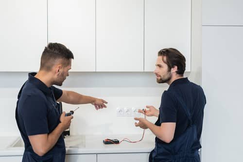 électricien Mantes-la-Ville - Deux électriciens devant une prise électrique