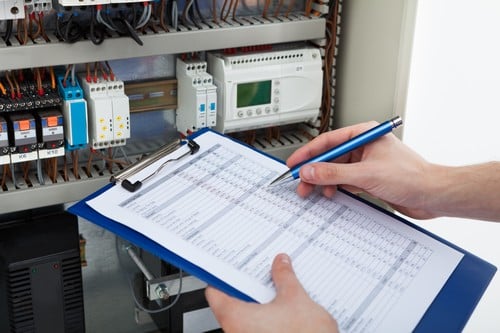 électricien Melun - un électricien prépare un devis en inspectant une installation électrique