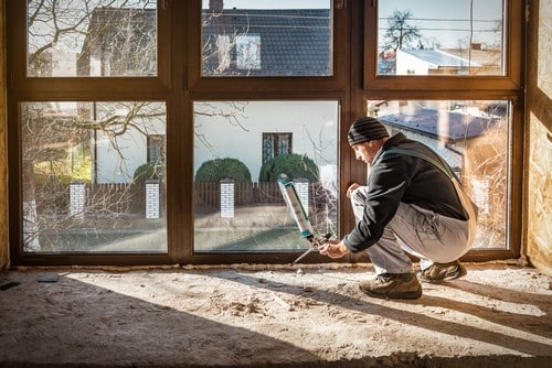 un artisan installe une baie vitrée en triple vitrage