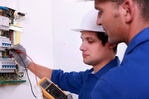 Électricien Carignan-de-Bordeaux - deux hommes qui réparent un tableau électrique