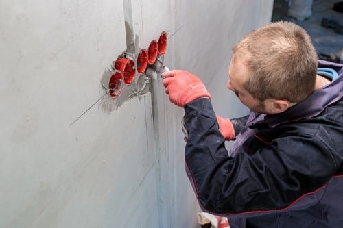 Electricien Lezennes - les bons artisans - électricien qui intervient sur des tuyaux qui sortent du mur