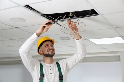 Electricien Lyon 1 - les bons artisans - électricien qui installe des fils électriques dans le plafond
