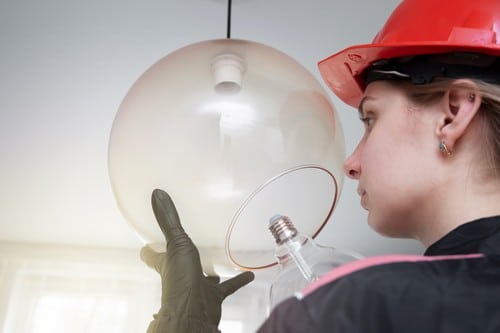 Electricien Paris 14 - les bons artisans - électricienne qui installe une ampoule dans une lampe