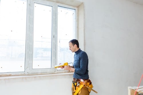 Vitrier Paris 4 - les bons artisans - vitrier qui applique du mastic sur le rebord d'une fenêtre