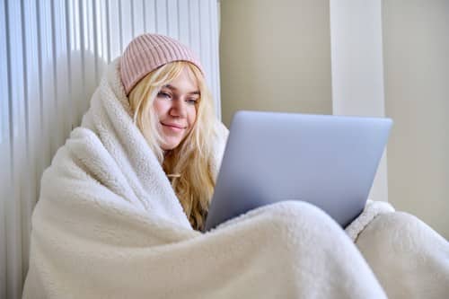 chauffagiste Aigremont - Une femme se réchauffe près de son radiateur