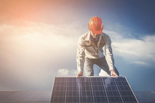 Electricien Noisy-le-Roi - homme sur un toit avec un panneau solaire