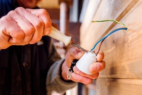 Electricien Wavrin - mains d'un homme qui réparent un objet avec câbles électriques
