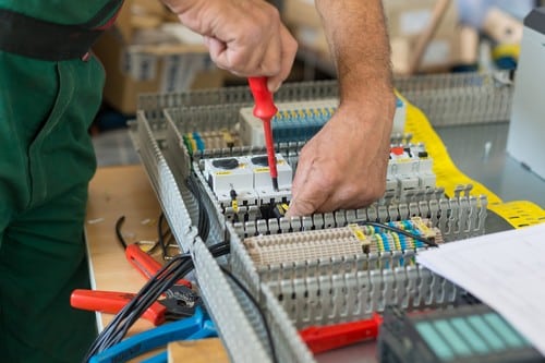 Electricien Anstaing - mains d'homme qui règle un tableau électrique