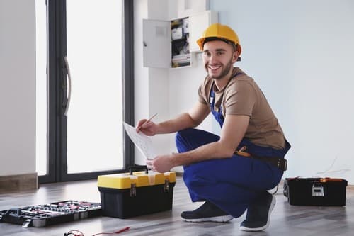 Electricien Houplines - homme qui sourit devant un tableau