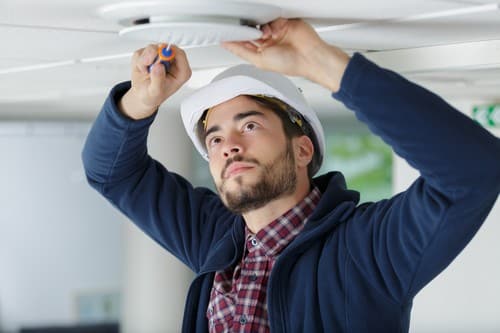 Electricien Houplines - homme qui règle un détecteur de fumée