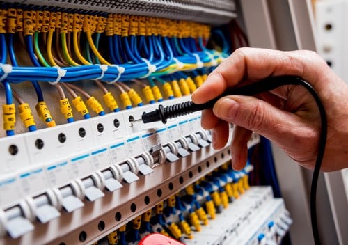 Electricien Le Vésinet - mains d'un homme qui règle les boutons d'un tableau électrique