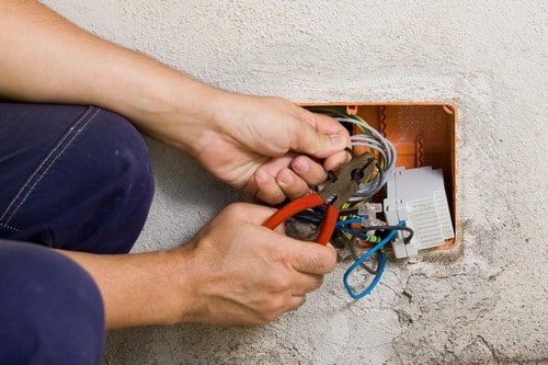 Electricien Mimet - Mains d'un homme qui règle des câbles électriques