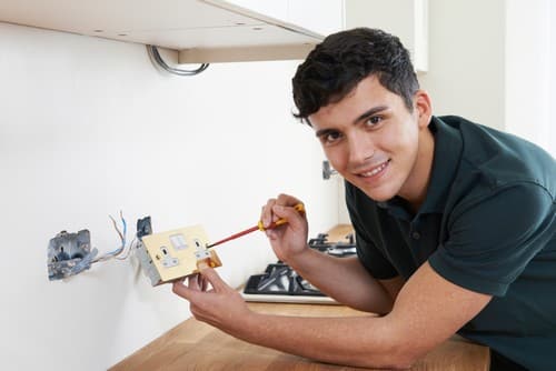 Electricien Paris 13 - homme qui vice une prise dans un mur