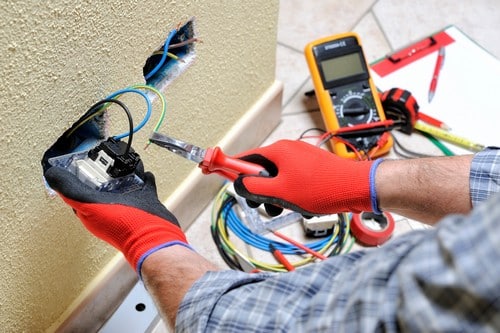 electricien saint-nom-la-bretèche - mains d'un homme qui règle une prise électrique murale