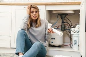 Une femme est perdue devant un problème avec son évier