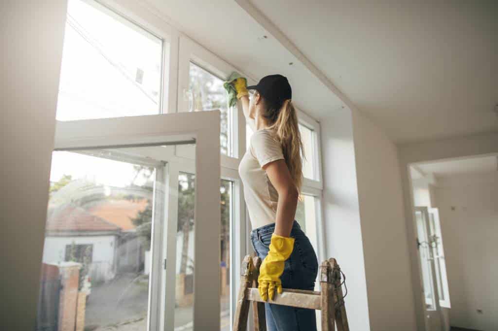 une femme pose un survitrage dans une maison en construction