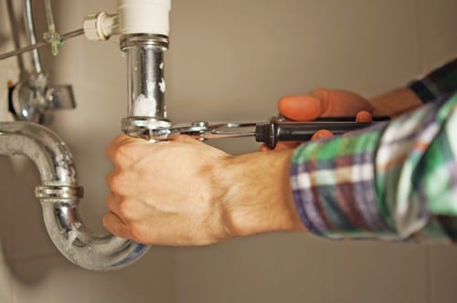 Plombier Fondettes - mains d'un homme qui répare une tuyauterie