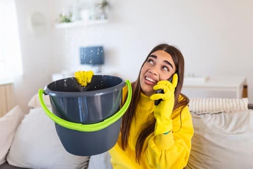 Plombier Gien - femme au téléphone qui porte un seau d'eau car il y a une fuite