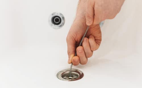 Plombier Nogent-le-Rotrou - mains d'un homme qui débouchent un lavabo