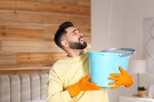 Plombier Saint-Amand-Montrond - homme qui tient un seau d'eau car il y a une fuite d'eau