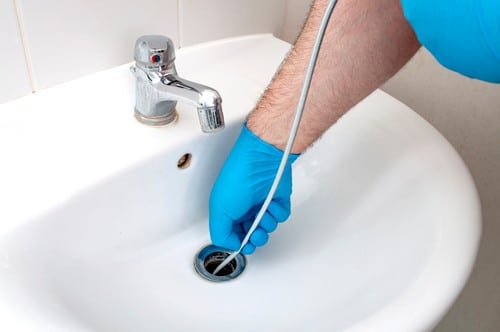 Plombier Saint-Jean-de-la-Ruelle - mains d'un homme qui débouche un lavabo