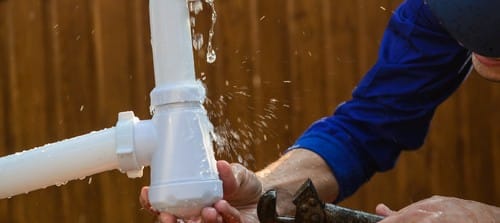 Plombier Vauréal - mains d'un homme qui règle une fuite d'eau
