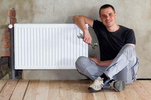 chauffagiste Vauréal - un homme assis à côté d'un radiateur neuf
